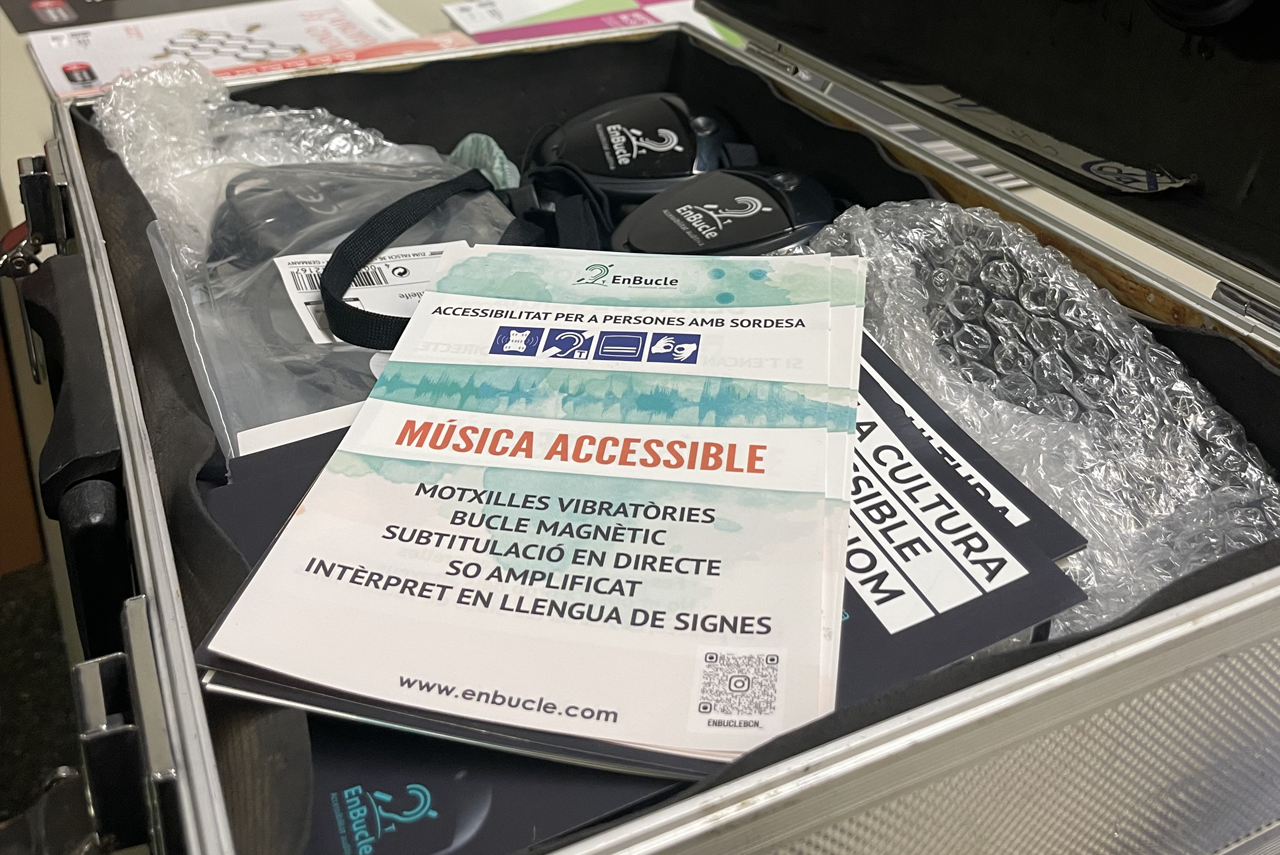 Maleta amb equips d’accessibilitat auditiva, amb motxilles vibratòries, receptors de bucle magnètic i fulletons informatius sobre música accessible.