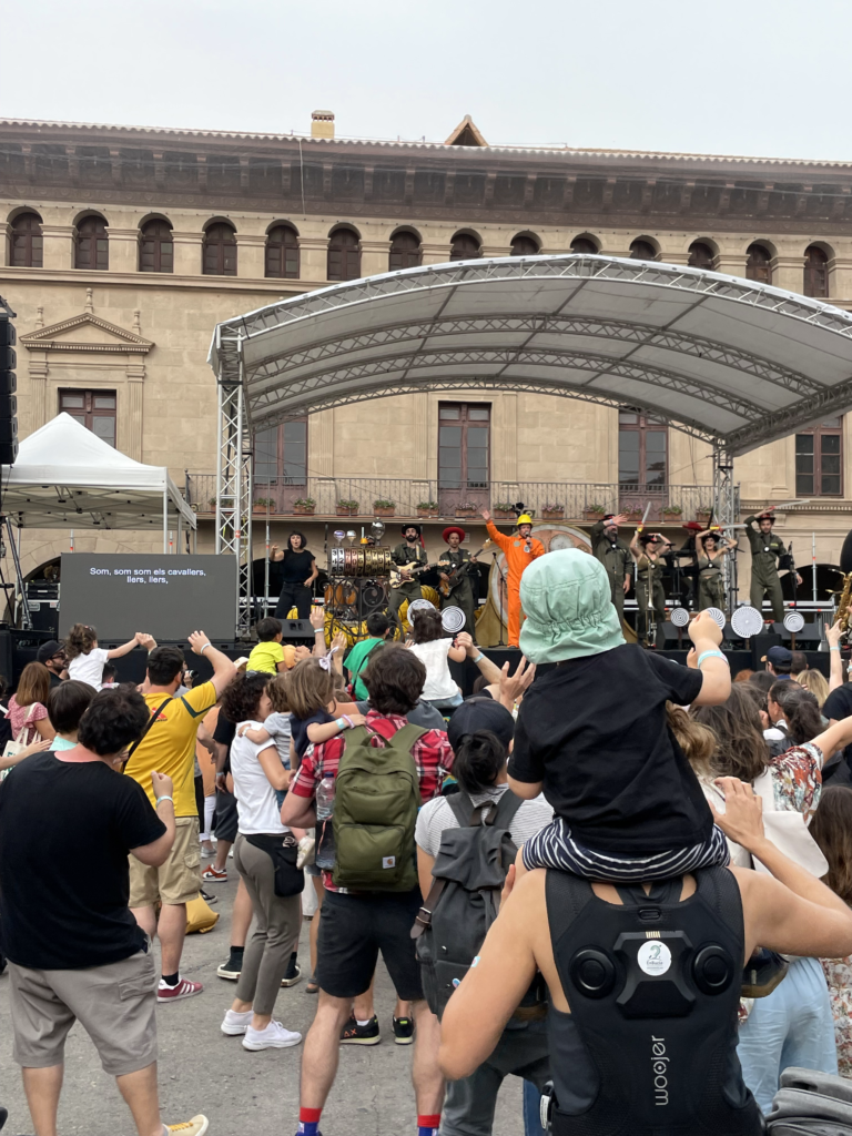 Concert a l’aire lliure amb públic i escenari, amb persones utilitzant motxilles vibratòries i interpretació en llengua de signes en directe.